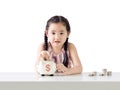 Asian little girl saving money in a piggy bank. Isolated on white background Royalty Free Stock Photo