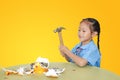 Asian little girl in school uniform breaking piggy bank isolated on yellow background at table. Schoolgirl with Money saving Royalty Free Stock Photo