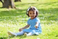 A asian little girl siting on green grass in park