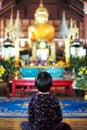 Asian little girl sits in front of the big golden buddha statues