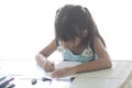 Asian little girl sitting doing homework at home isolated on white background. Royalty Free Stock Photo