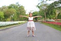 Asian little girl standing on road in the garden with open hands wide with flowers around the garden Royalty Free Stock Photo