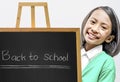 Asian little girl standing with a small chalkboard on a wooden easel