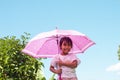 Asian girl standing with an umbrella with joyfulness while it is raining and sunny during the day.