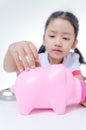 Asian little girl in Thai student uniform putting coins to piggy Royalty Free Stock Photo