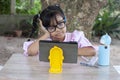 Asian little girl is using tablet and puts her hands over his head due to the feeling tired of online learning at home. Royalty Free Stock Photo