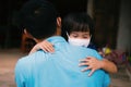 Asian little girl wearing protective face mask hugging her father on rural home background, family love and care lifestyles amid