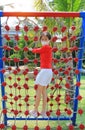 Asian little girl wearing a protective mask while playing on climbing rope net outdoor. Rear view Royalty Free Stock Photo