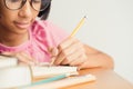 Asian little girl wears glasses while sit writing on desk at her home