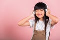 Asian little kid 10 years old smiling listening music wearing wireless headset Royalty Free Stock Photo