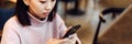 Asian lovely girl climb on the phone in a coffee shop. A pretty beautiful woman is looking for information on the Royalty Free Stock Photo