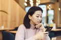 Asian lovely girl climb on the phone in a coffee shop. A pretty beautiful woman is looking for information on the Internet or Royalty Free Stock Photo