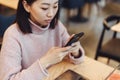 Asian lovely girl climb on the phone in a coffee shop. A pretty beautiful woman is looking for information on the Internet or Royalty Free Stock Photo