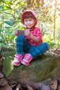 Asian lovely girl using smart phone on boulder over nature background. Outdoors, travel on vacation. Royalty Free Stock Photo