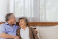 Asian lovely happy senior couple grandfather and grandmother hugging or cuddling on sofa in living room at home. Joyful elderly