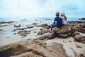 Asian lovers happy on the beach.The sky is bright Travel nature and sitting relax on the rocks at the sea at phuket. in Thailand.