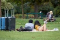 Asian loving couple of tourists with suitcases lies on the green grass in the park. The Champ de Mars in Paris Royalty Free Stock Photo