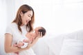 Asian loving mom carying of her newborn baby at home. Happy mum holding sleeping infant child on hands. Mother hugging her little Royalty Free Stock Photo