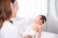 Asian loving mom carying of her newborn baby at home. Happy mum holding sleeping infant child on hands. Mother hugging her little Royalty Free Stock Photo