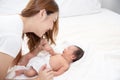 Asian loving mom carying of her newborn baby at home. Happy mum holding sleeping infant child on hands. Mother hugging her little Royalty Free Stock Photo