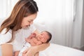 Asian loving mom carying of her newborn baby at home. Happy mum holding sleeping infant child on hands. Mother hugging her little Royalty Free Stock Photo