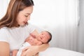 Asian loving mom carying of her newborn baby at home. Happy mum holding sleeping infant child on hands. Mother hugging her little Royalty Free Stock Photo