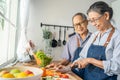 Asian loving senior elderly couple wear apron and cooking in kitchen. Attractive strong old man and woman grandparent wear