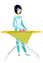 Asian maid ironing clothes on ironing board. Royalty Free Stock Photo