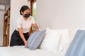 Asian maid setting up pillow on bed sheet in hotel room Royalty Free Stock Photo