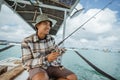 Asian male angler checks his reel before fishing Royalty Free Stock Photo