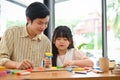 Asian male art teacher is teaching a girl to sculpt and mould plasticine into different shapes