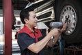 An Asian male auto technician is changing car wheel at service garage. Royalty Free Stock Photo