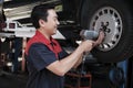 An Asian male auto technician is changing car wheel at service garage. Royalty Free Stock Photo