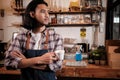 Asian male barista stands at a casual cafe, looking outside with a coffee cup