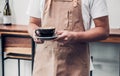 Asian male barista wear apron holding hot coffee cup served to c Royalty Free Stock Photo