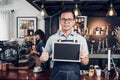 Asian male barista wear jean apron thumbs up at blank blackboard