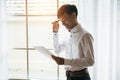 Asian male businessman reading business contract documents in private workroom.