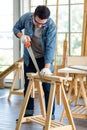 Asian male carpenter woodworker engineer in jeans outfit with safety gloves and glasses goggles using hand saw cutting wood stick Royalty Free Stock Photo