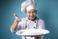 Asian Male Chef Shows Empty White Plate, Presenting Something, Copy Space Royalty Free Stock Photo