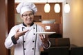 Asian Male Chef Shows Empty White Plate, Presenting Something, Copy Space Royalty Free Stock Photo