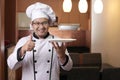 Asian Male Chef Shows Empty White Plate, Presenting Something, Copy Space Royalty Free Stock Photo