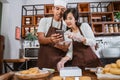 Asian male chef shows smartphone to female chef while preparing donut orders