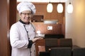 Asian male chef smiling friendly when welcoming customer to his restaurant, successful chef in culinary restaurant business