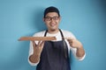 Asian Male Chef or Waiter Shows Empty Wooden Plate, Presenting Something, Copy Space Royalty Free Stock Photo