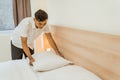 Asian male cleaning staff tidying pillows on bed Royalty Free Stock Photo