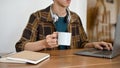 Asian male college student or freelancer working on his project on laptop while sipping coffee Royalty Free Stock Photo