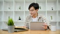 Asian male college student in library co-working space, using digital tablet Royalty Free Stock Photo