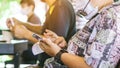 Asian male customer wear face mask take off glasses and use smartphone while sit in waiting social distance queue for take away