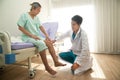 An Asian male doctor examining the reactions of an Asian male patient. neurologist using a knee hammer which is a medical device. Royalty Free Stock Photo