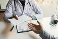 Asian male doctor talking in clinic room and handing a prescription to the patient Royalty Free Stock Photo